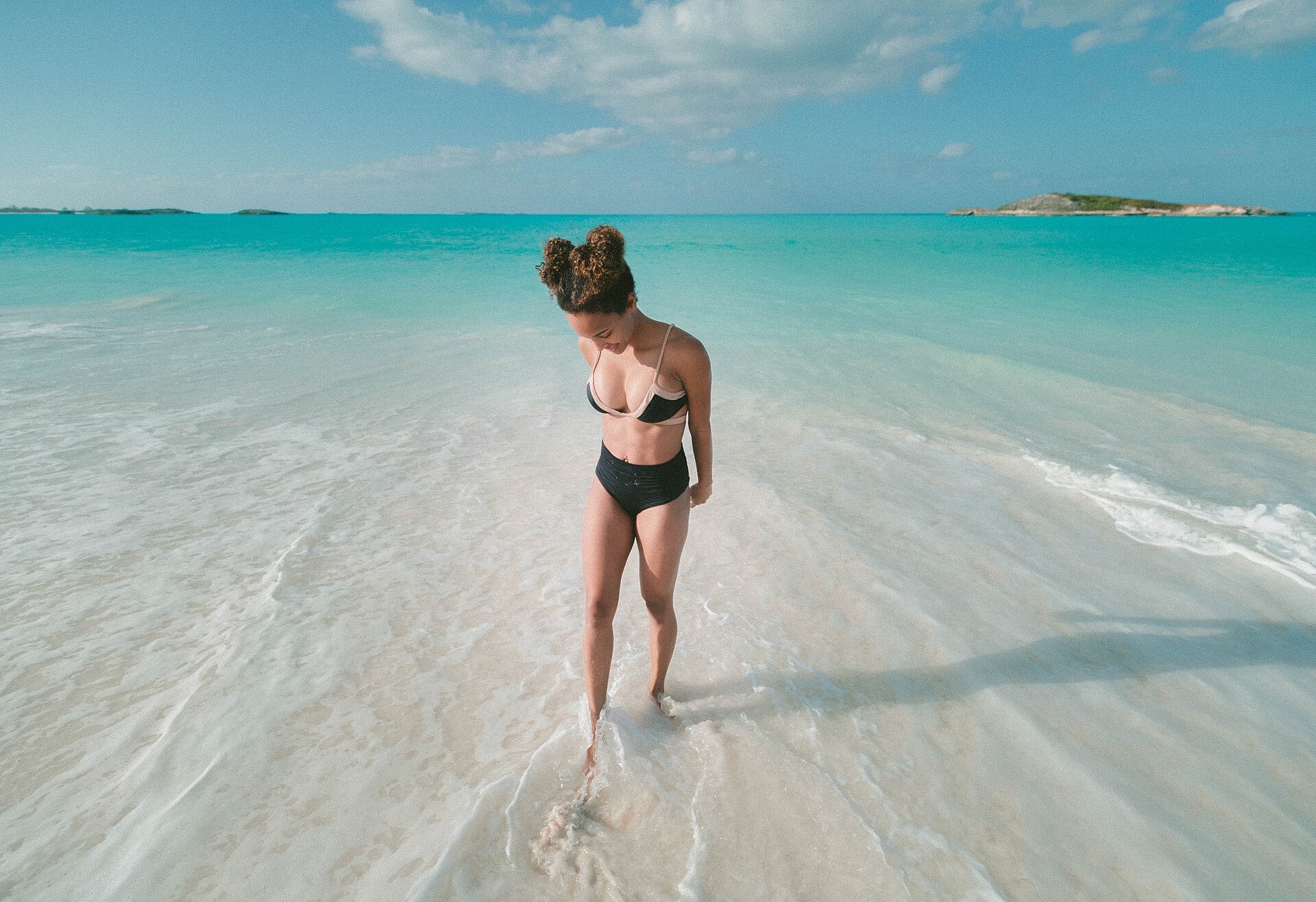 Shallow turquoise water over a white sandbar off Great Exuma Island, with a low cay on the horizon