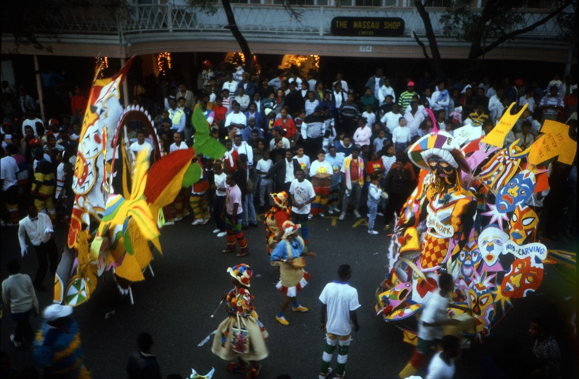 Junkanoo dancers in large crepe-paper costumes parading in daylight on Bay Street in Nassau