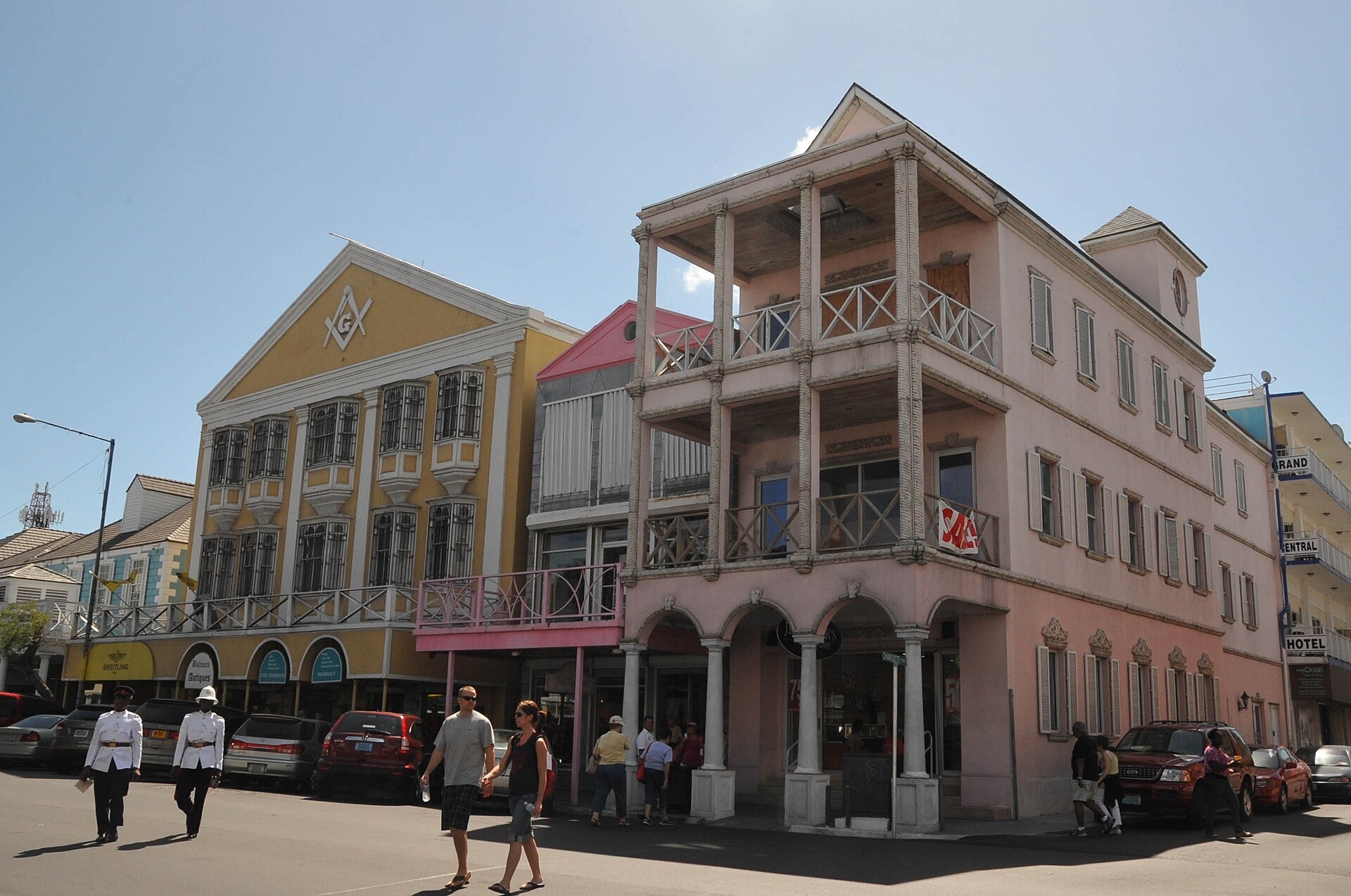 Pink and white colonial building on Bay Street in downtown Nassau, with pedestrians on the sidewalk